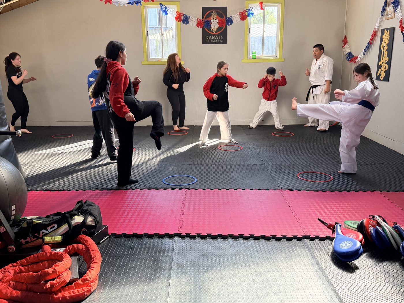 Clase de Karate Kyokushin con patadas dentro del dojo, con el cartel de Kyokushin al fondo